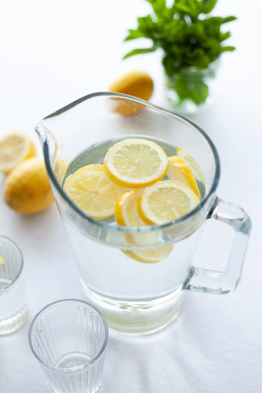 glass pitcher filled with water and slices of lemon